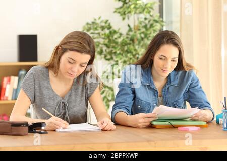 Due studiosi agli studenti di studiare la scrittura e la lettura delle note a casa Foto Stock