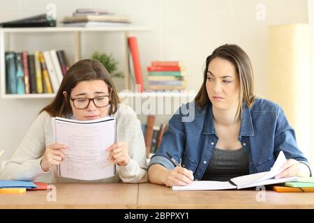 Studente con problemi di vista e un altro disprezzando il suo mentre sono lo studio a casa Foto Stock