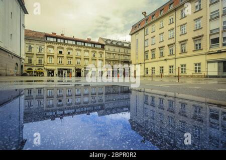 Zagabria, Croazia - 16 aprile 2020 : riflessione degli edifici in un pozze sulla strada dopo la pioggia nel centro di Zagabria, Croazia. Foto Stock