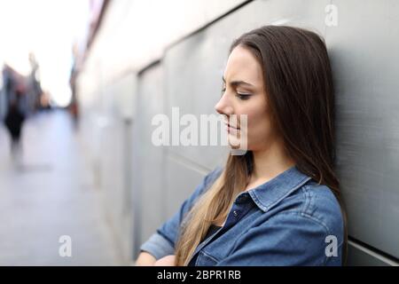 Vista laterale verticale di una ragazza triste lamenta da sola per la strada Foto Stock