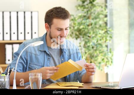 Imprenditore aprendo una busta imbottita in un desktop in ufficio Foto Stock