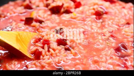 Close-up di un Italiano cremoso Risotto di barbabietole e agitando il cucchiaio di legno. Foto Stock