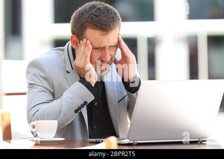 Dirigenti stanchi di sofferenza mal di testa lavorando sulla linea seduti in un caffè Foto Stock