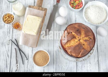 Il Panettone con gli ingredienti sul bianco tavolo in legno Foto Stock