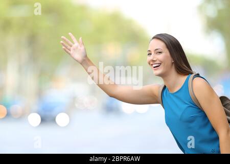 Una donna felice che si affaccia taxi sulla strada Foto Stock