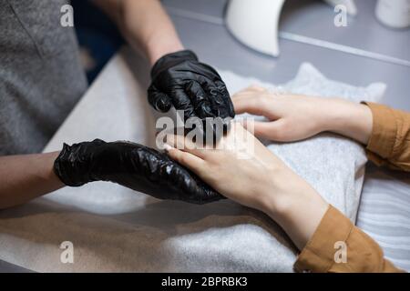 Primo piano di un manicure che fa massaggio idratante e mani per un cliente. Il tema è cura della pelle e bellezza del corpo. Concetto di Spa e manicure. Pelle morbida Foto Stock