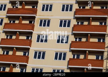 La parete di un alto edificio di mattoni casa, balconi rosso e pareti di colore giallo. Foto Stock