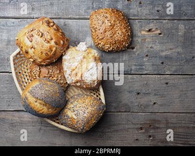 Assortimento di gustosi panini organico in un cesto su un rustico tavolo da cucina Foto Stock