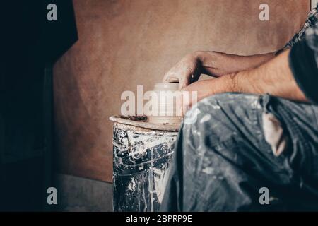 L'uomo forma il vaso di argilla sulla ruota del vasaio. Potter nel processo di lavoro vista laterale Foto Stock