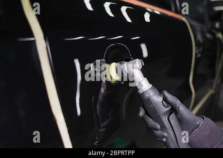 Processo di lucidatura degli specchi con una lucidatrice e cera. Rimozione dei graffi dalla carrozzeria di un'auto Foto Stock