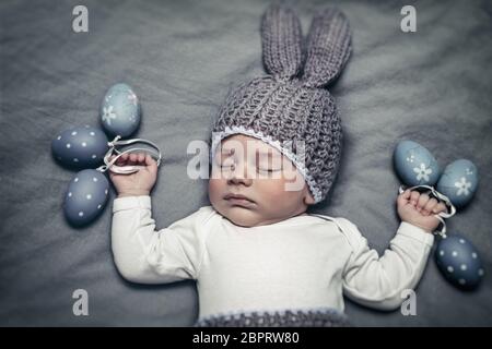 Ritratto di un piccolo grazioso baby boy indossando bunny costume e trattenimento uova decorative in mani, felice vacanza di Pasqua Foto Stock