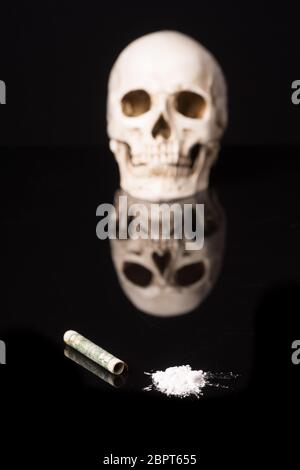 La cocaina o altre droghe illegali che vengono rilevati per mezzo di un tubo e il cranio, isolato su nero sfondo lucido Foto Stock