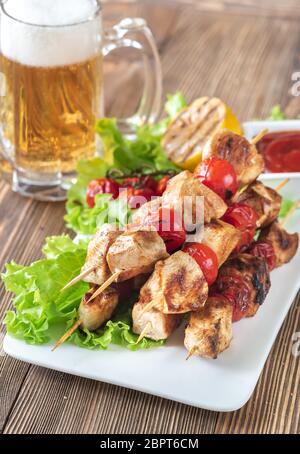 Grigliate gli spiedini di pollo con la tazza di birra Foto Stock