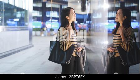 Donna che guarda attraverso la finestra e la scelta dei prodotti all'interno, concetto di shopping finestra Foto Stock