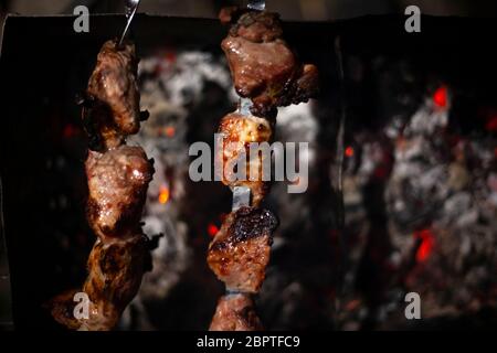 La carne viene fritta su un fuoco aperto. Gli spiedini impostati sugli spiedini vengono cucinati su un mongal. Cucina nazionale dei popoli caucasici. Deliziosa carne dà ju Foto Stock