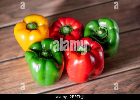 molti peperoni freschi grandi organici diversi colori rosso giallo e verde su una tavola di legno Foto Stock