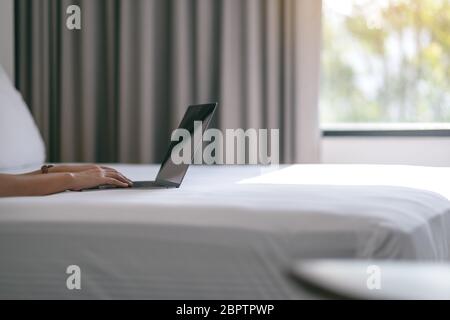 Immagine di una donna in primo piano utilizzando e digitando sul computer portatile sul letto Foto Stock