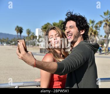 Una coppia romantica che scatta foto al telefono cellulare in una cittadina tropicale sulla spiaggia Foto Stock