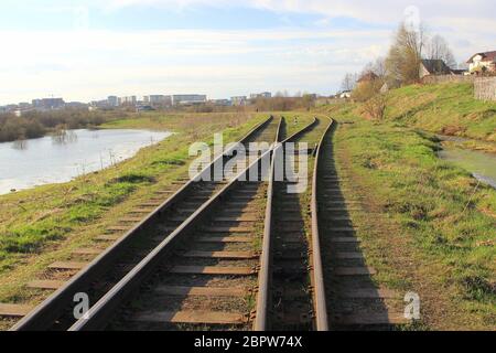 La ferrovia si estende in lontananza sullo sfondo di giovani verdi erba e alberi in primavera. Foto Stock