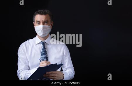 Un uomo che indossa la maschera medica e lavora da casa Foto Stock