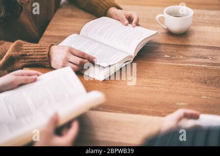 Gruppo di persone sedute e ci è piaciuta molto la lettura di libri insieme sul tavolo di legno Foto Stock