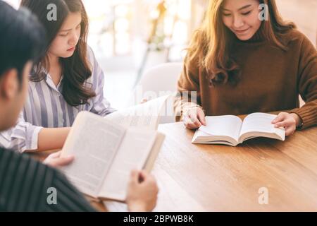 Gruppo di persone sedute e goduto la lettura libro insieme sul tavolo di legno Foto Stock