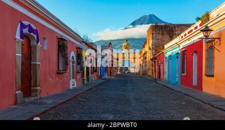 Panorama Alba nella strada principale di Antigua City con l'Arco di Santa Catalina e il vulcano Agua, Guatemala. Foto Stock