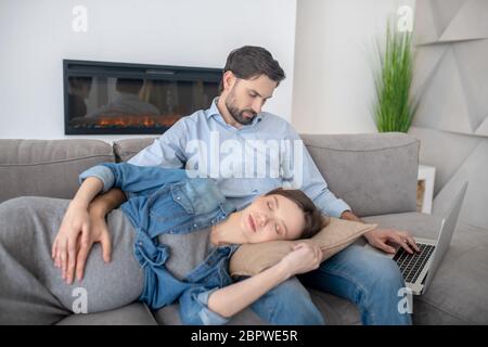 Giovane donna incinta in giacca jeans che dorme sui giri dei mariti Foto Stock