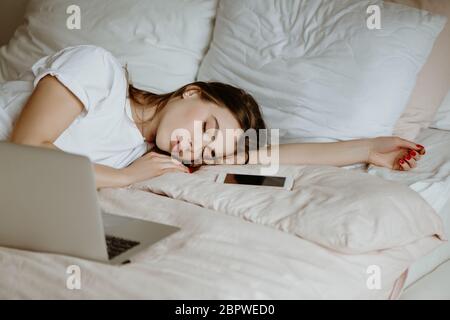 Yound bella donna si addormentò mentre usando il computer a letto a casa. Foto Stock