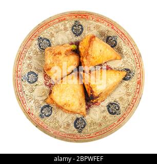 Cucina indiana - vista dall'alto del keema samosas (pasticceria salata fritta ripiena di carne e verdure) su piatto di ottone isolato su sfondo bianco Foto Stock