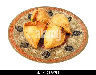 Cucina indiana - porzione di samosas di verdure (pasticceria salata fritta ripiena di purè di patate e verdure) su piatto di ottone isolato su sfondo bianco Foto Stock