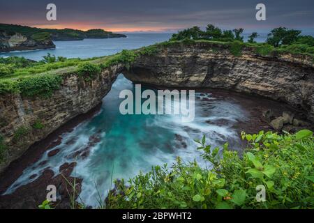 Spiaggia rotta sull'isola di Nusa Penida all'alba. Presa con una lunga esposizione durante l'alba. Nusa Penida è una piccola isola con un'isola bella e ruvida Foto Stock