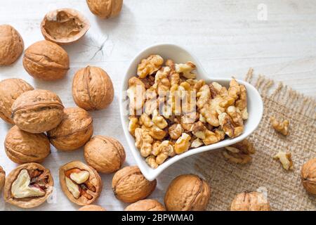 Noci biologiche nel cuore su sfondo di legno Foto Stock