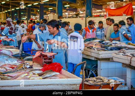 Dubai, Emirati Arabi Uniti - 19 Febbraio 2016. Lavoratori in uniforme si preparano a vendere la cattura quotidiana nella trafficata sezione di pesce fresco del mercato Waterfront. Foto Stock