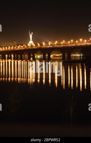 Vista notturna del ponte sull'ampio fiume Dnipro a Kiev su una lunga esposizione Foto Stock