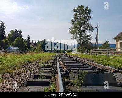 Bella strada ferroviaria di montagna a scartamento ridotto, rotaie nelle montagne dei Carpazi che attraversano la foresta nel villaggio di Vorohta, Ivano Foto Stock