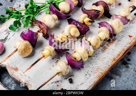 Funghi alla griglia su spiedini di legno. Ortaggio shish kebab Foto Stock