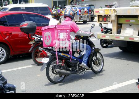 Antipolo City, Filippine - 16 maggio 2020: Il conducente che consegna il cibo del motociclo trasporta gli ordini del cliente durante l'epidemia di virus Covid 19. Foto Stock