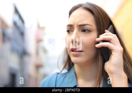 Preoccupato della donna parlando su smart phone all'aperto a piedi in strada Foto Stock