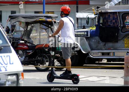 Antipolo City, Filippine - 16 maggio 2020: L'uomo guida uno scooter elettrico per spostarsi, poiché i trasporti pubblici sono stati vietati durante il Covid 19 Foto Stock