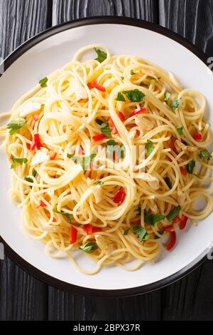 Gli spaghetti aglio e olio sono un semplice piatto italiano di aglio, olio d'oliva, prezzemolo da vicino in un piatto sul tavolo. Vista dall'alto verticale Foto Stock