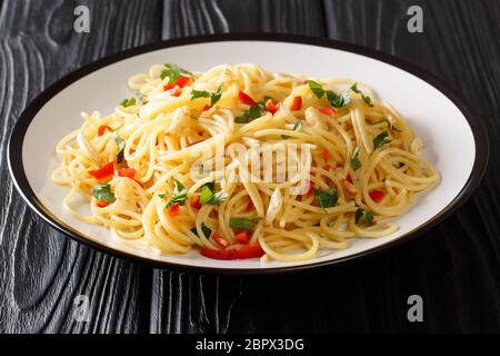 Ricetta per la classica pasta di aglio e olio con aglio fritto, prezzemolo e pepe caldo primo piano in un piatto sul tavolo. Orizzontale Foto Stock