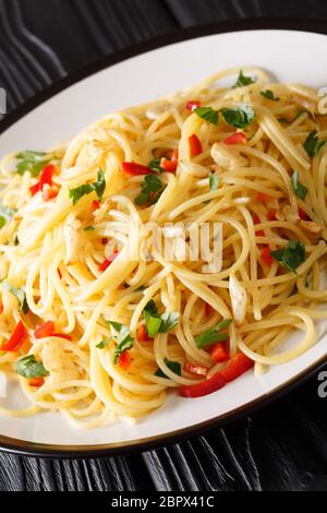 Gli spaghetti aglio e olio sono un semplice piatto italiano di aglio, olio d'oliva, prezzemolo da vicino in un piatto sul tavolo. Verticale Foto Stock