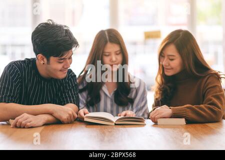 Un gruppo di giovani goduto la lettura dello stesso libro insieme Foto Stock