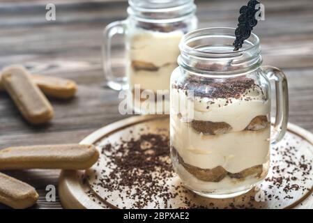 Il tiramisù in vasetti di vetro sullo sfondo di legno Foto Stock