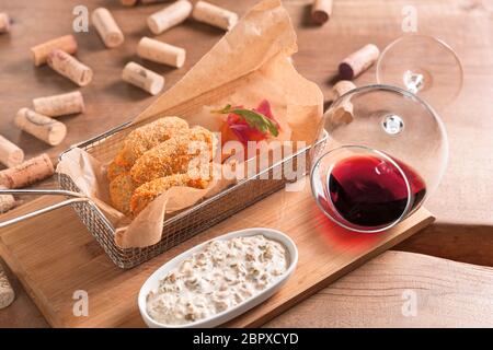 Linguetta di panning di carne di vitello con insalata di yogurt e vino rosso, servita in una carta riciclata su una tavola di legno. Foto Stock