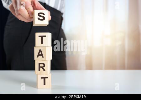 Canto femminile di mettere il cubo di legno blocco con parole START sul tavolo. Business start e concetto di successo Foto Stock