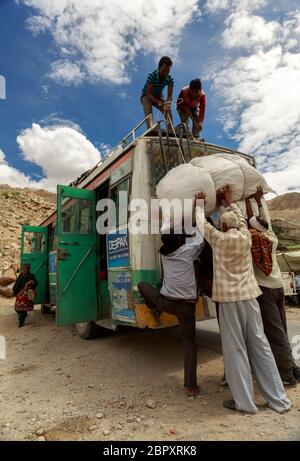 Persone che caricano bagagli sulla cima dell'autobus utilizzando il tecnico locale a Nako, Himachal Pradesh, India Foto Stock