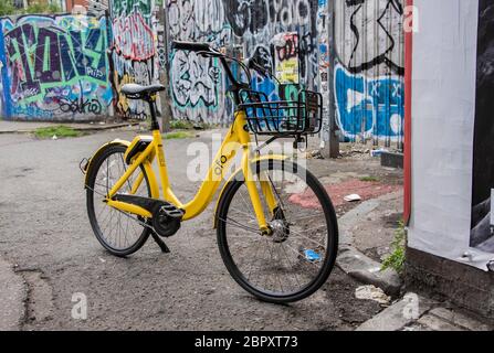 Biciclette parcheggiate in strada di fronte al muro coperto di graffiti a Shoreditch, Londra Foto Stock