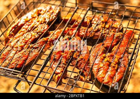 Grigliare il salmone bistecca con lo zenzero marinata in griglia al di sopra del barbecue. Vista dall'alto di salmone alla griglia su flaming braai Foto Stock